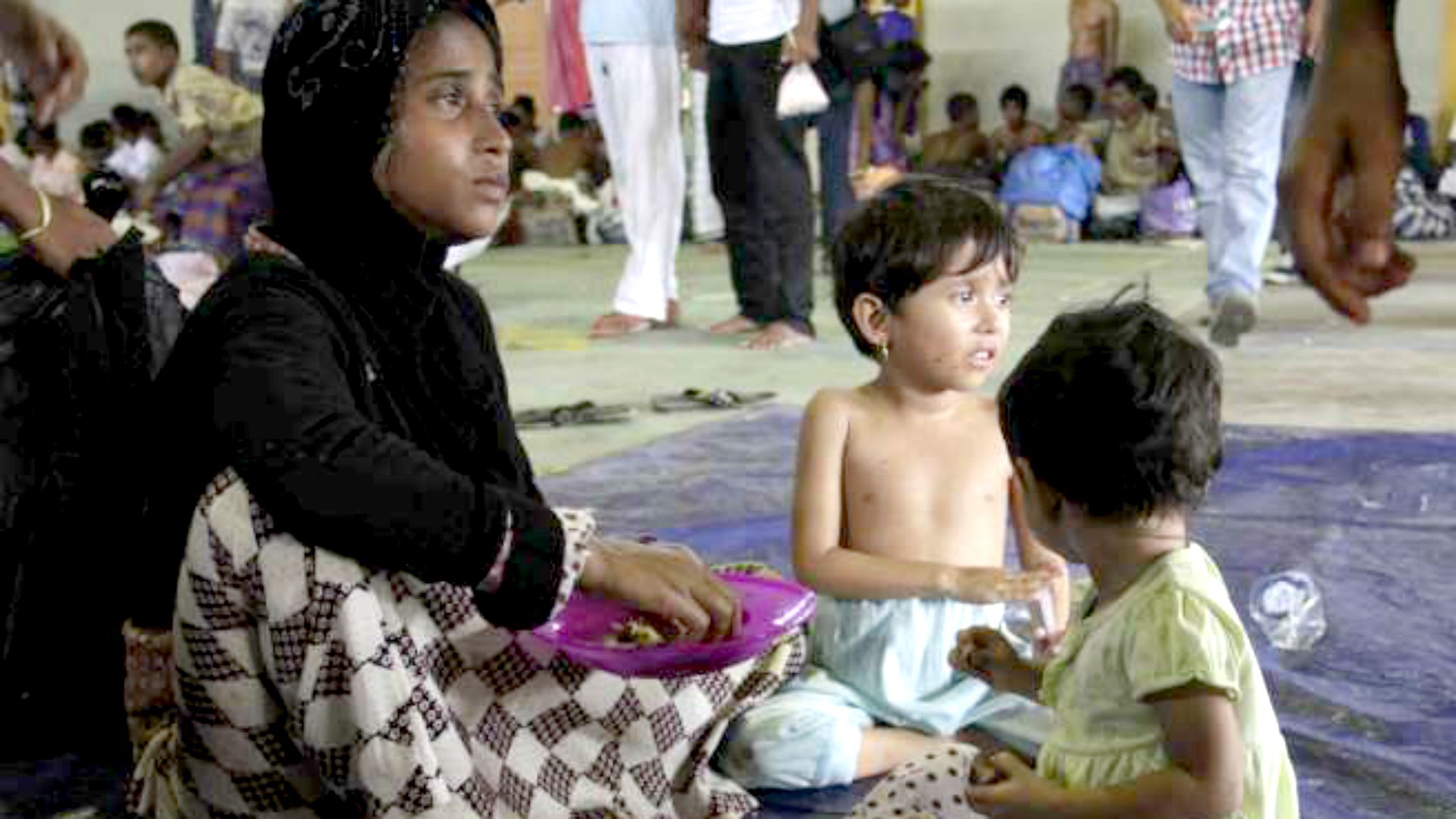 Une femme et ses deux enfants secourus en mer mangent la nourriture qui leur est offerte dans un centre à Kuala Cangkoi, en Indonésie (Photo: HCR) 