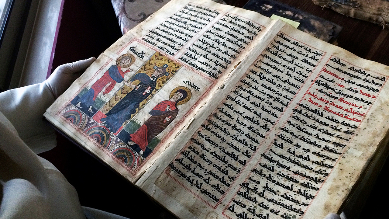 Le Père Najeeb Michaeel montre un des manuscrits chrétiens qu’il a pu sauver |  © npr.org