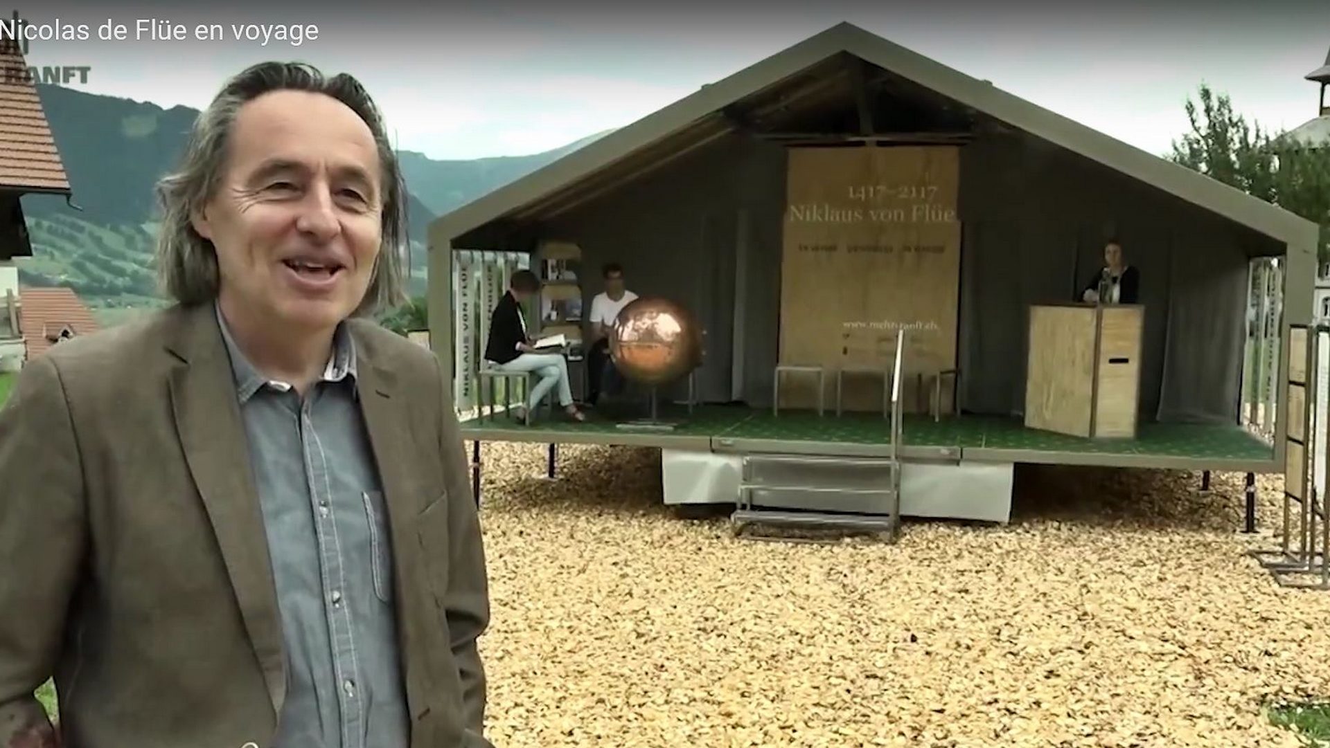 Otto Steiner devant le pavillon mobile 'Nicolas de Flüe en voyage' (capture d'écran Youtube)