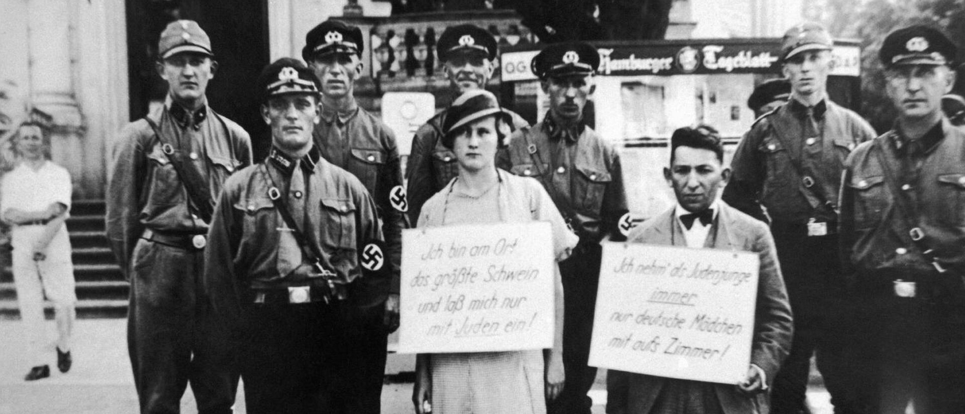 Persécution des juifs en Allemagne nazie. Sur les pancartes on peut lire: "Je suis la plus grosse truie. Je ne m'acoquine qu'avec des juifs." "Jeune homme juif, je ne prends que des jeunes filles allemandes dans ma chambre." | © domaine public 