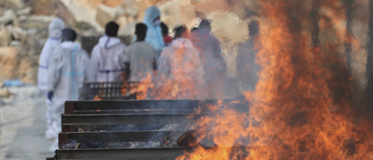 En Inde, les membres d'une famille rendent les derniers hommages à un proche, autour d'un crématorium installé dans la rue | © AP Photo/Aijaz Rahi/Keystone