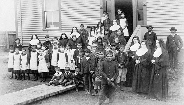 Foyer fédéral de Port Harrison (Inukjuak); un groupe d’élèves, des sœurs et des hommes autochtones, Québec, vers 1890 | Domaine public