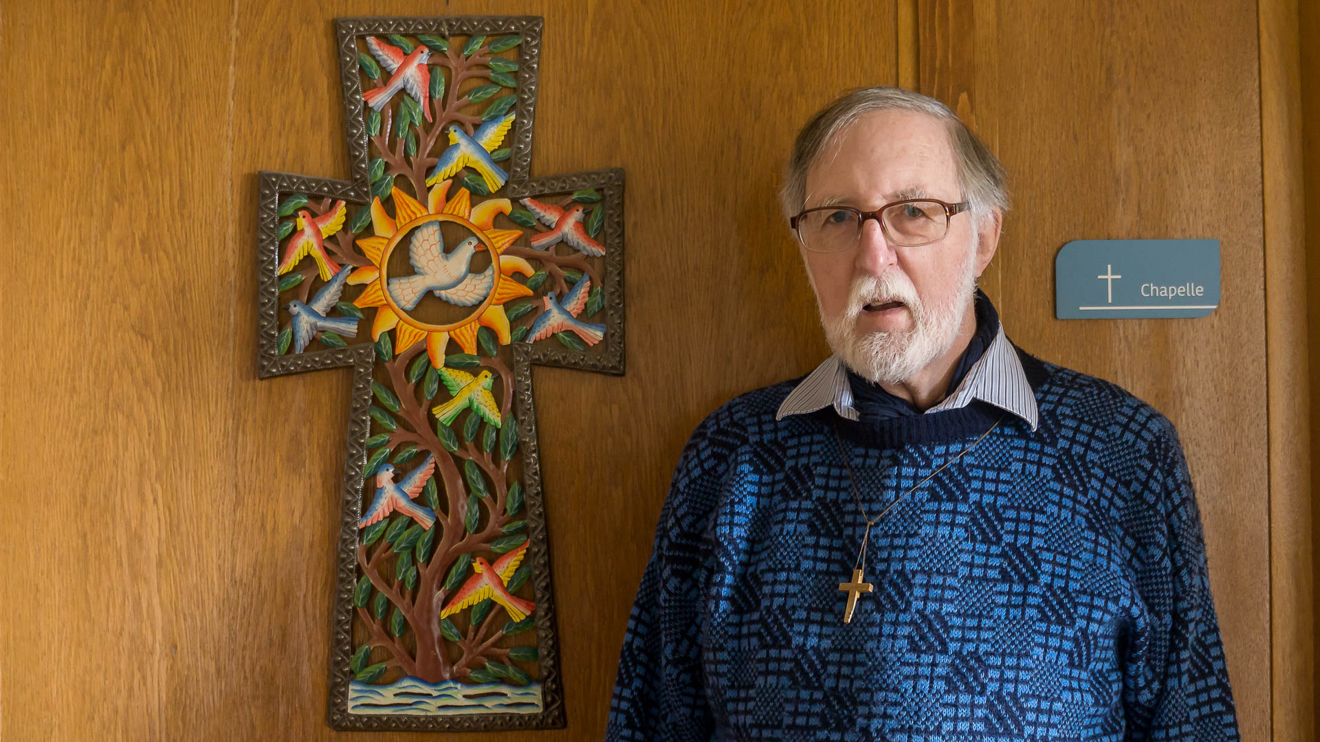 Le Père Georges Conus devant une croix décorée ramenée d'Haïti | © Maurice Page