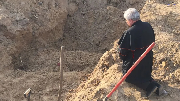 Le cardinal Krajewski prie au bord d'une fosse commune au nord de Kiev | Vatican Media 