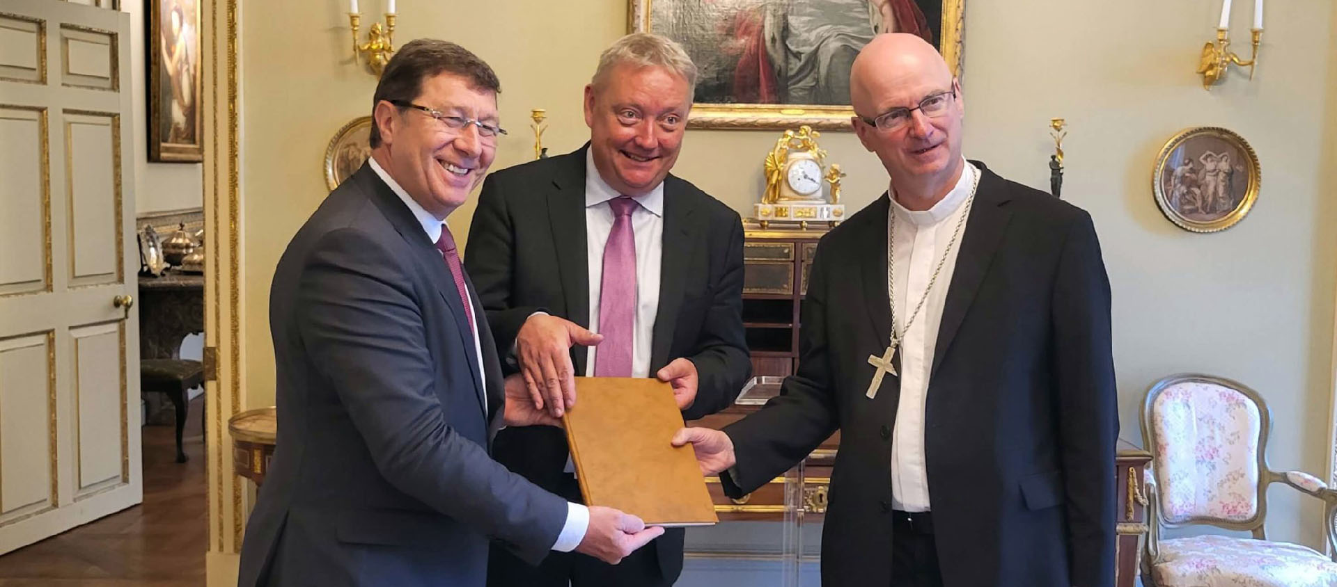 Mgr Morerod et Pierre Flückiger, l'archiviste cantonal de Genève, ont remis les archives du vicariat épiscopal de Genève au conseiller d'État Mauro Poggia | © diocèse LGF