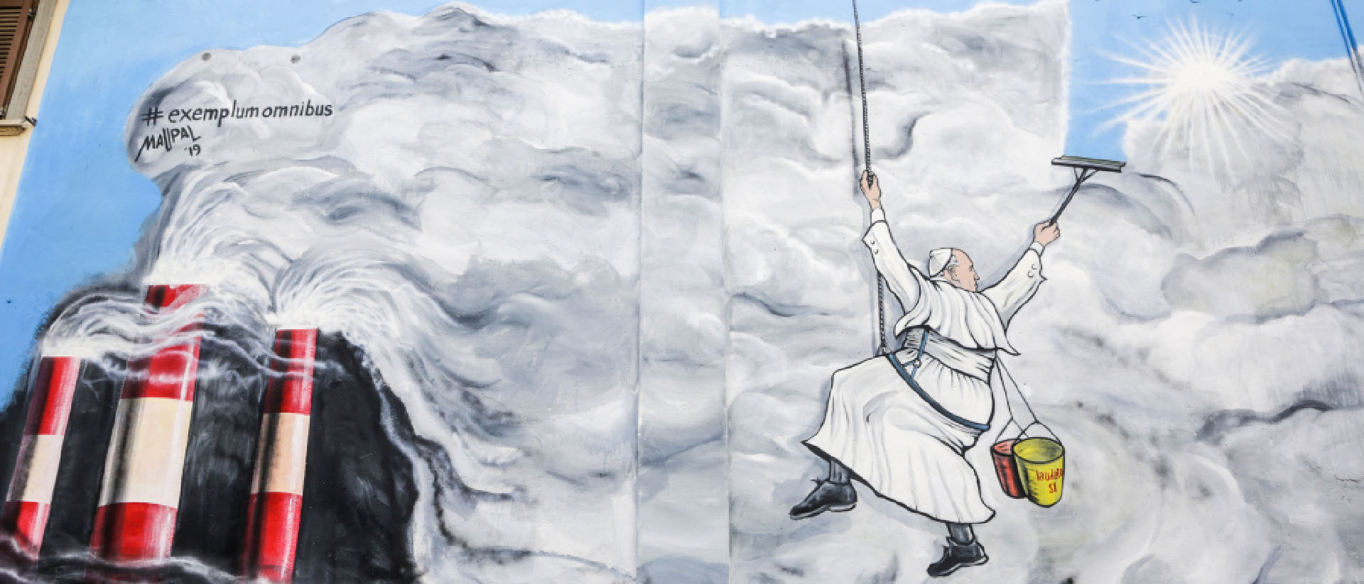 Une fresque réalisée par  Maupal en 2019 à Albano (Italie). Le pape François,  en laveur de carreaux, nettoie les nuages de smog pour laisser apparaître le ciel bleu et le soleil | DR