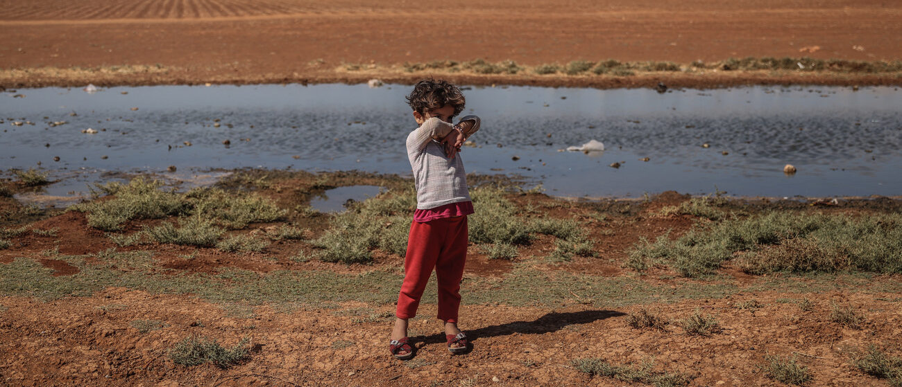 Un enfant devant un plan d'eau insalubre, à Idlib (Syrie), en septembre 2022 | © KEYSTONE/DPA/Anas Alkharboutli