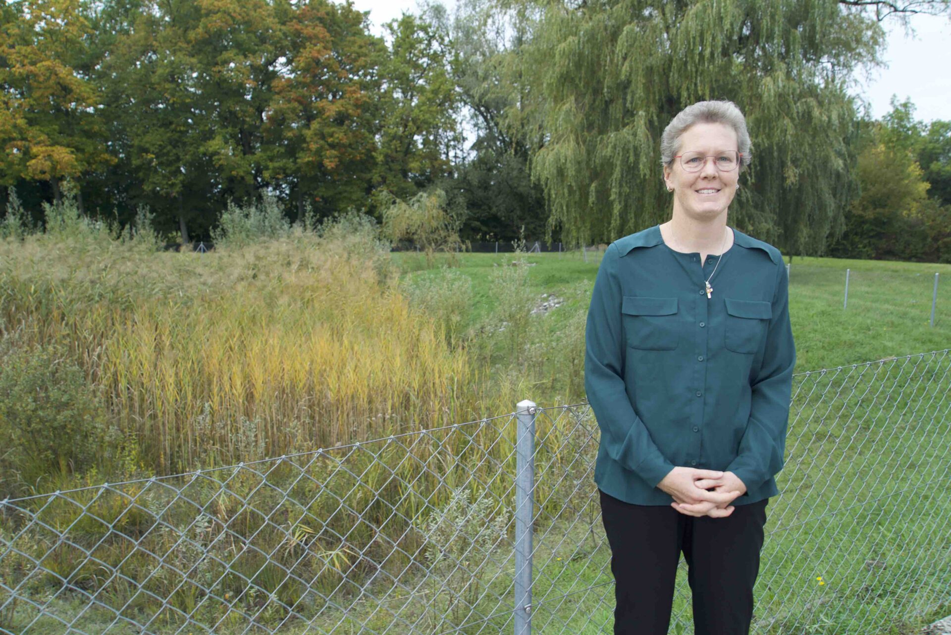L’aumônière Carol Beytrison devant les arbres qui bordent la prison de la Brenaz, à Genève | © Lucienne Bittar