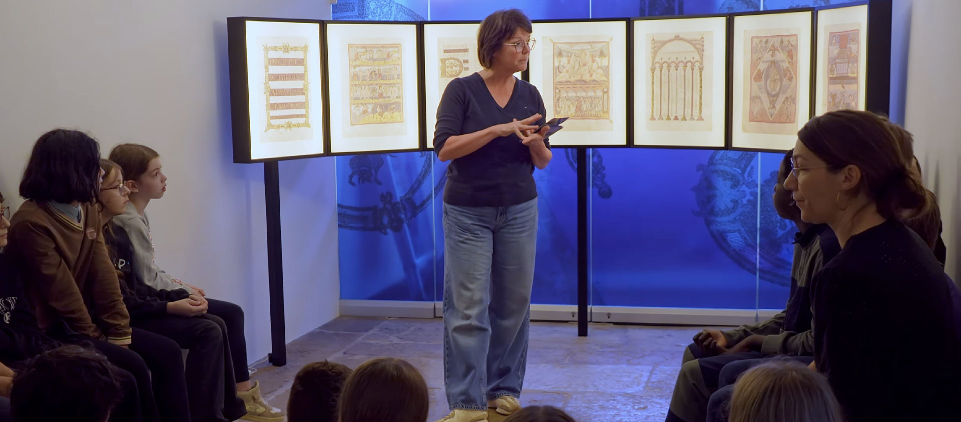 Valérie Rais, médiatrice culturelle au Musée jurassien d'art et d'histoire, dialogue avec les jeunes d'une classe sur la Bible de Moutier-Grandval | © Jean-Claude Boillat