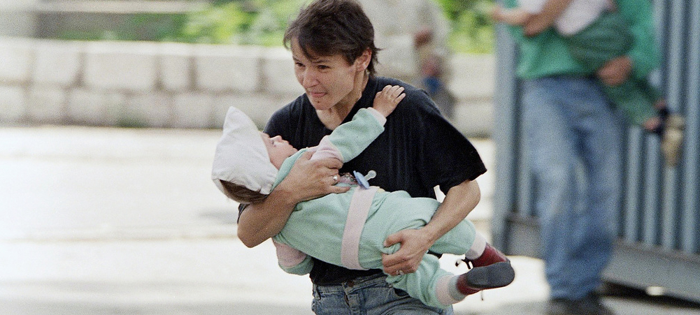 De riches "touristes" ont-ils payé pour tirer sur des civils à Sarajevo, dans les années 1990? | photo: une mère et son enfant tentent de se mettre à l'abri des balles dans la ville assiégée de Sarajevo, en juin 1995 © KEYSTONE/AP/David Brauchli
